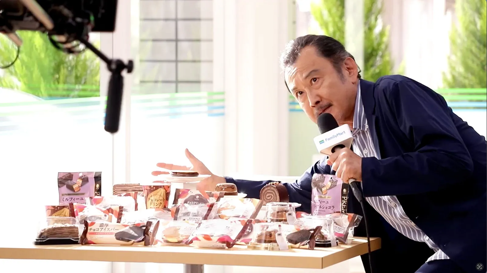 吉田鋼太郎&八木莉可子も絶賛!ファミマ「チョコだらけ」全11品で“3度しあわせ”を体験 3 女性がFamilyMartの商品の前でマイクを持って話している様子。テーブルには様々なスイーツが並んでいる。