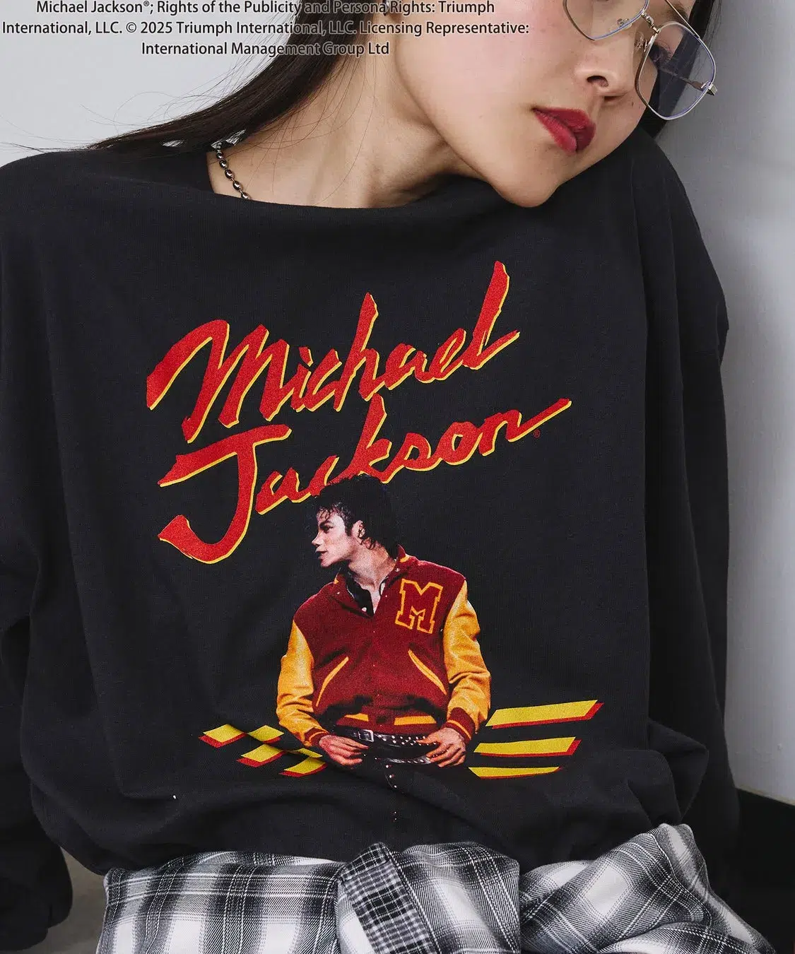 「KING OF POP」を纏う!ROSE BUDがマイケル・ジャクソン特別コレクションを初発表、ジェンダーレスで楽しめる全貌を公開! 6 マイケル・ジャクソンのプリントが施された黒いスウェットシャツを着た女性のクローズアップ写真。
