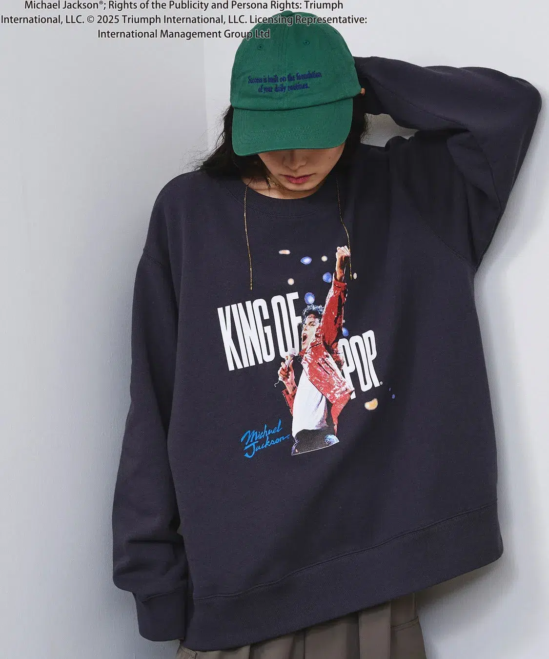 「KING OF POP」を纏う!ROSE BUDがマイケル・ジャクソン特別コレクションを初発表、ジェンダーレスで楽しめる全貌を公開! 2 マイケル・ジャクソンのプリントが施された紺色のトレーナーを着た女性の写真。