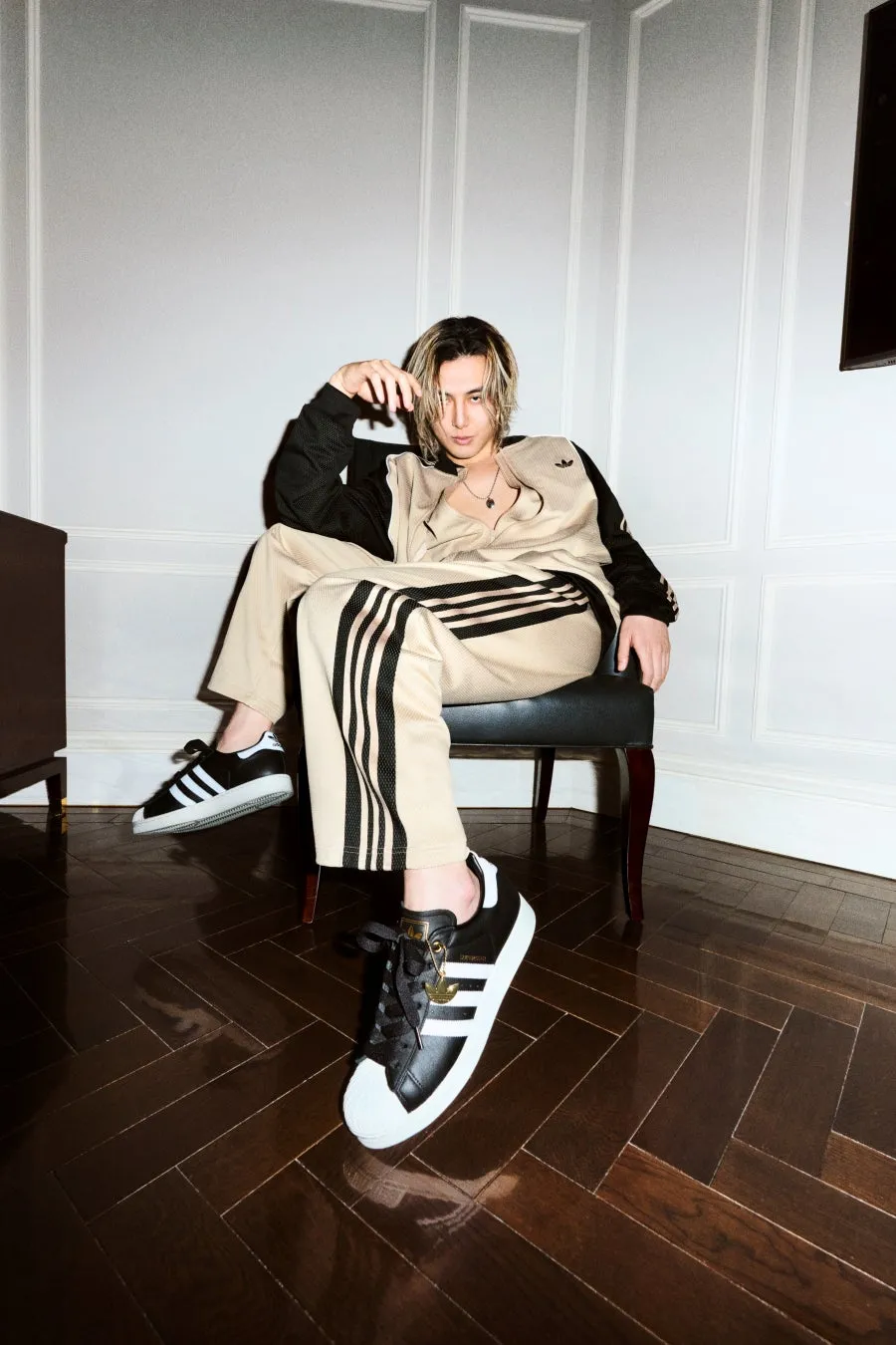 藤井風・JENNIEコメントあり!adidas SUPERSTAR新章開幕、原宿に限定フォトスポットも登場! 6 アディダスのトラックスーツを着た男性が椅子に座ってポーズをとっている写真です。