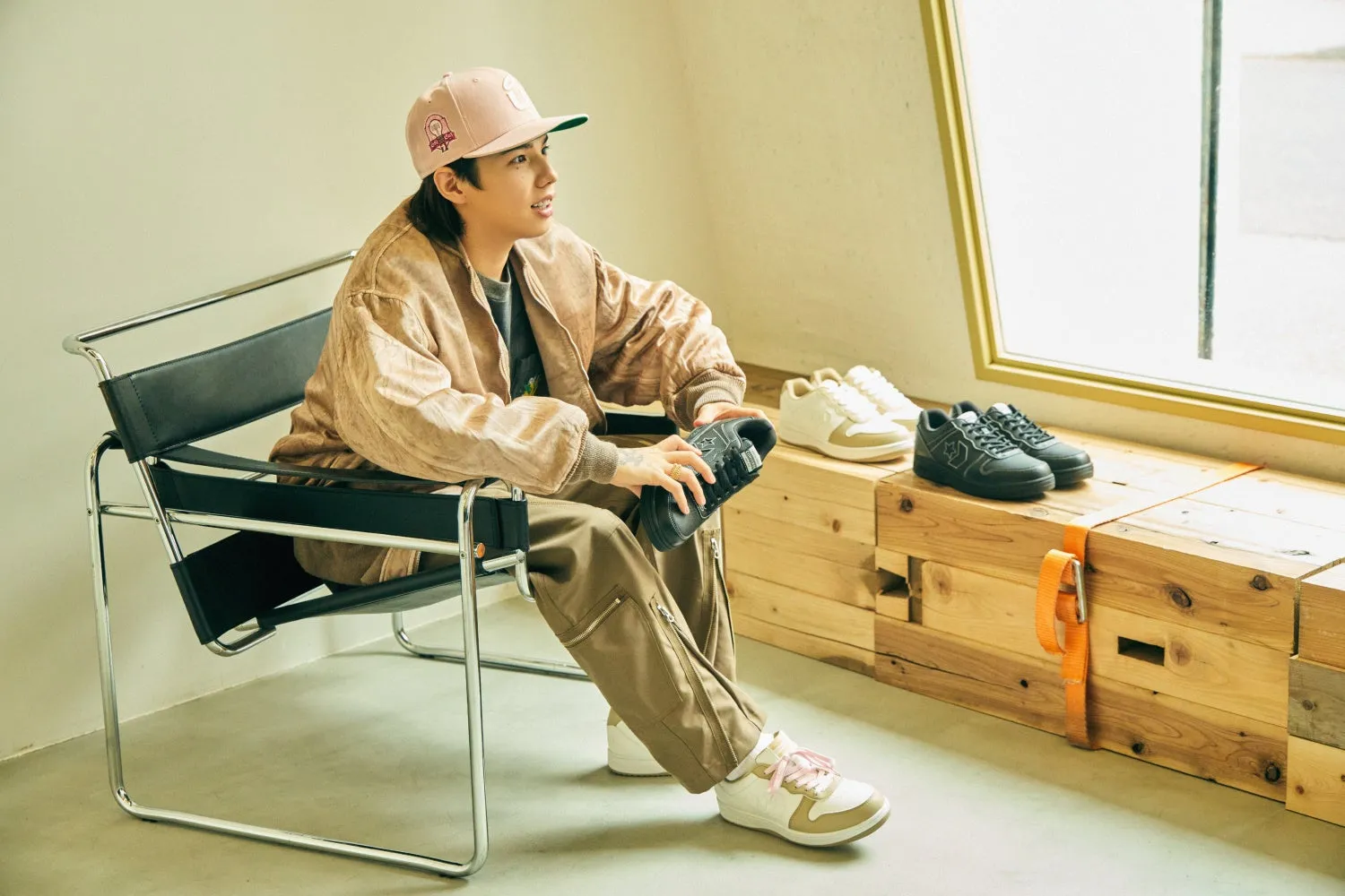 男性が椅子に座り、靴を手にしてポーズをとっている写真