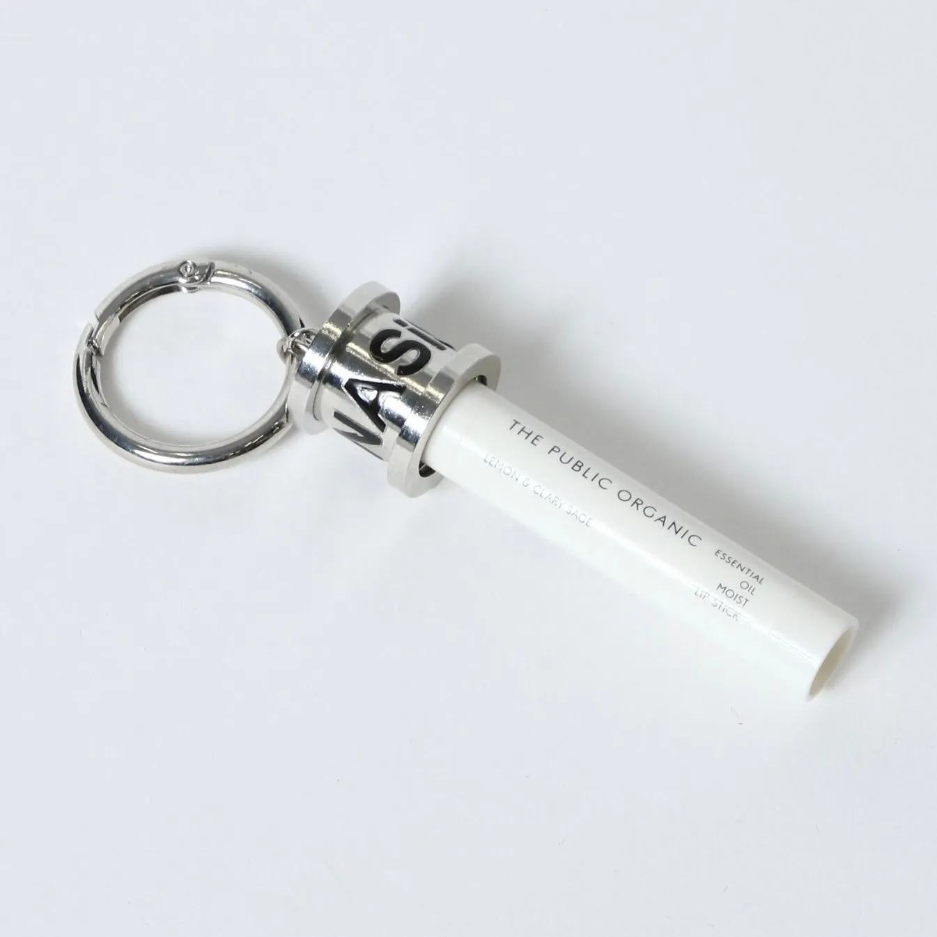 白いリップスティックとキーホルダーが写った画像です。リップスティックには「THE PUBLIC ORGANIC」と「LEMON & CLARY SAGE」の文字が印字されています。キーホルダーはシルバー色です。