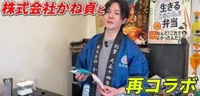 男性が弁当と書かれた看板の前で、青い法被を着て、何かを持って立っている様子