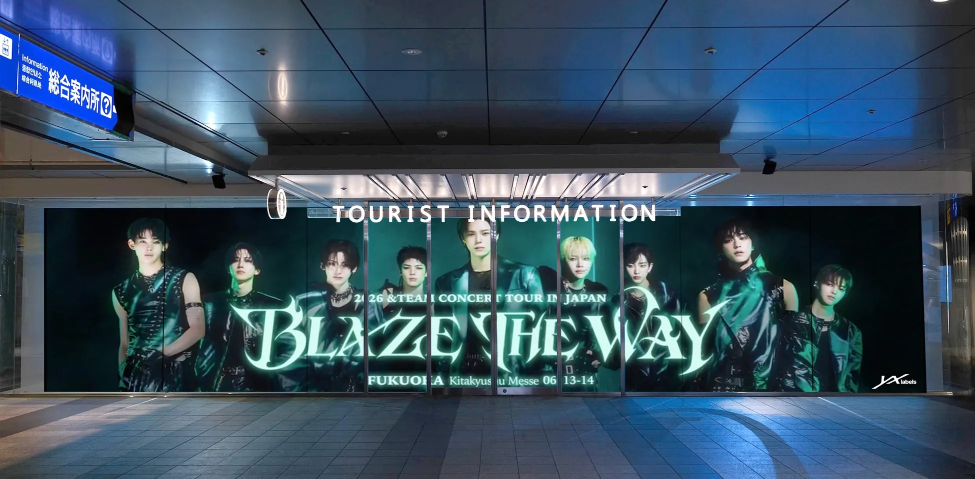 &TEAM、北九州・小倉駅が「聖地」に大変身!ファン必見の体験型イベントで街を"BLAZE THE WAY"! 1 Blaze the Wayツアーの広告。複数の男性アイドルグループのメンバーが写っている。広告は観光案内所の壁に設置されている。