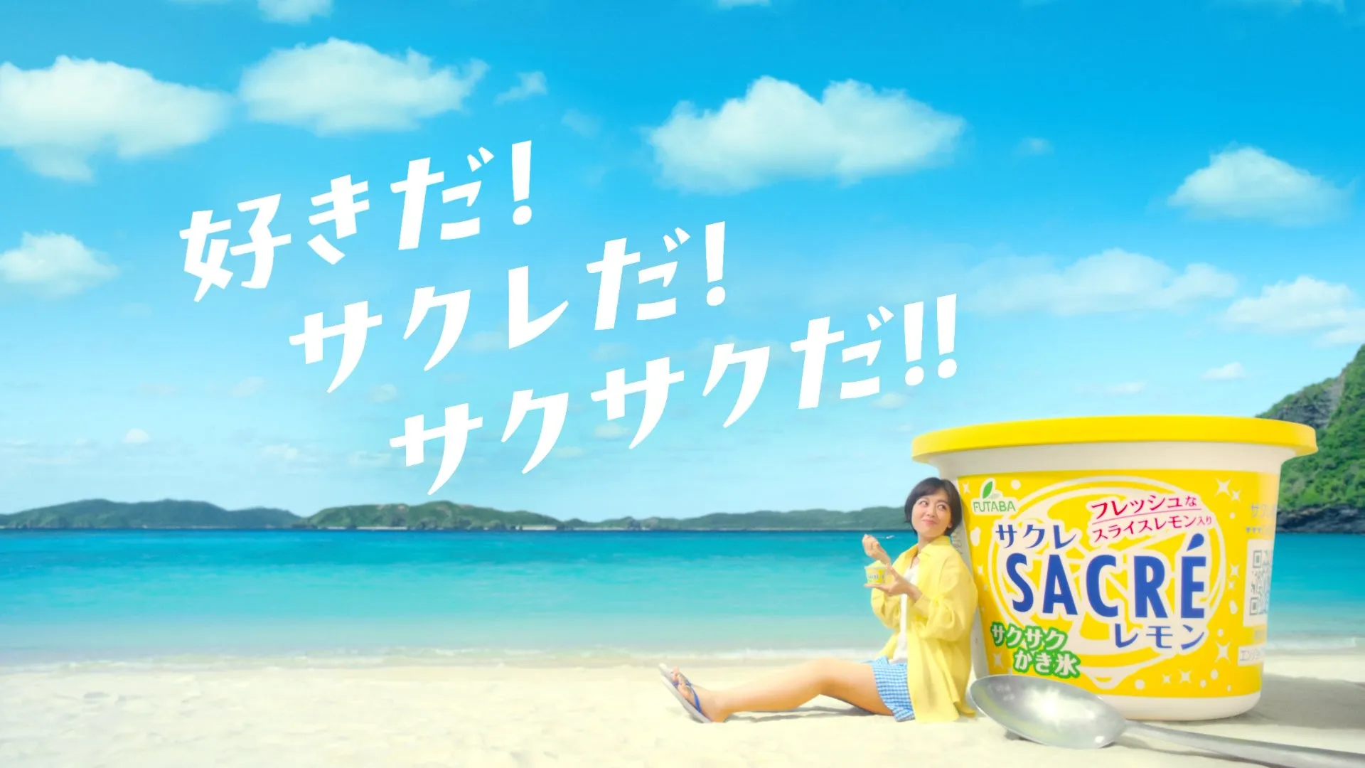 伊原六花がビーチで「だーい好き!」と告白!発売41年目の国民的アイス「サクレレモン」新CMが公開 1 ビーチで女性がサクレレモンのかき氷を食べている広告画像。空には「好きだ!サクレだ!サクサクだ!!」の文字が書かれている。